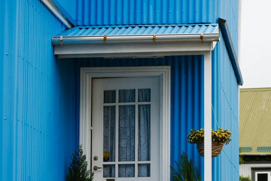 Frente de una casa pintado de azul con puerta blanca