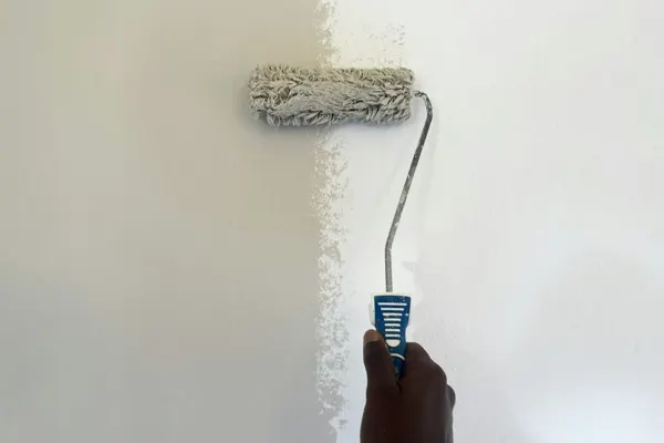 Rodillo pintando de blanco una pared interior