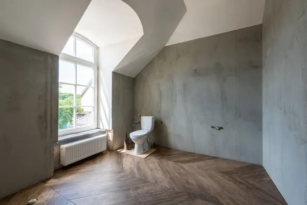 Baño con paredes revestidas en microcemento gris