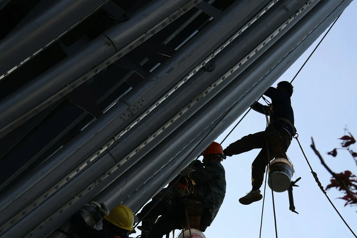 Pintores colgados en silleta trabajando en un edificio